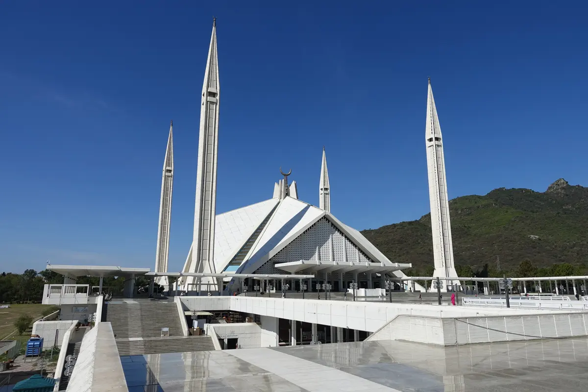 The white tent-like shell and four minarets of Faisal Mosque against the Margalla Hills
