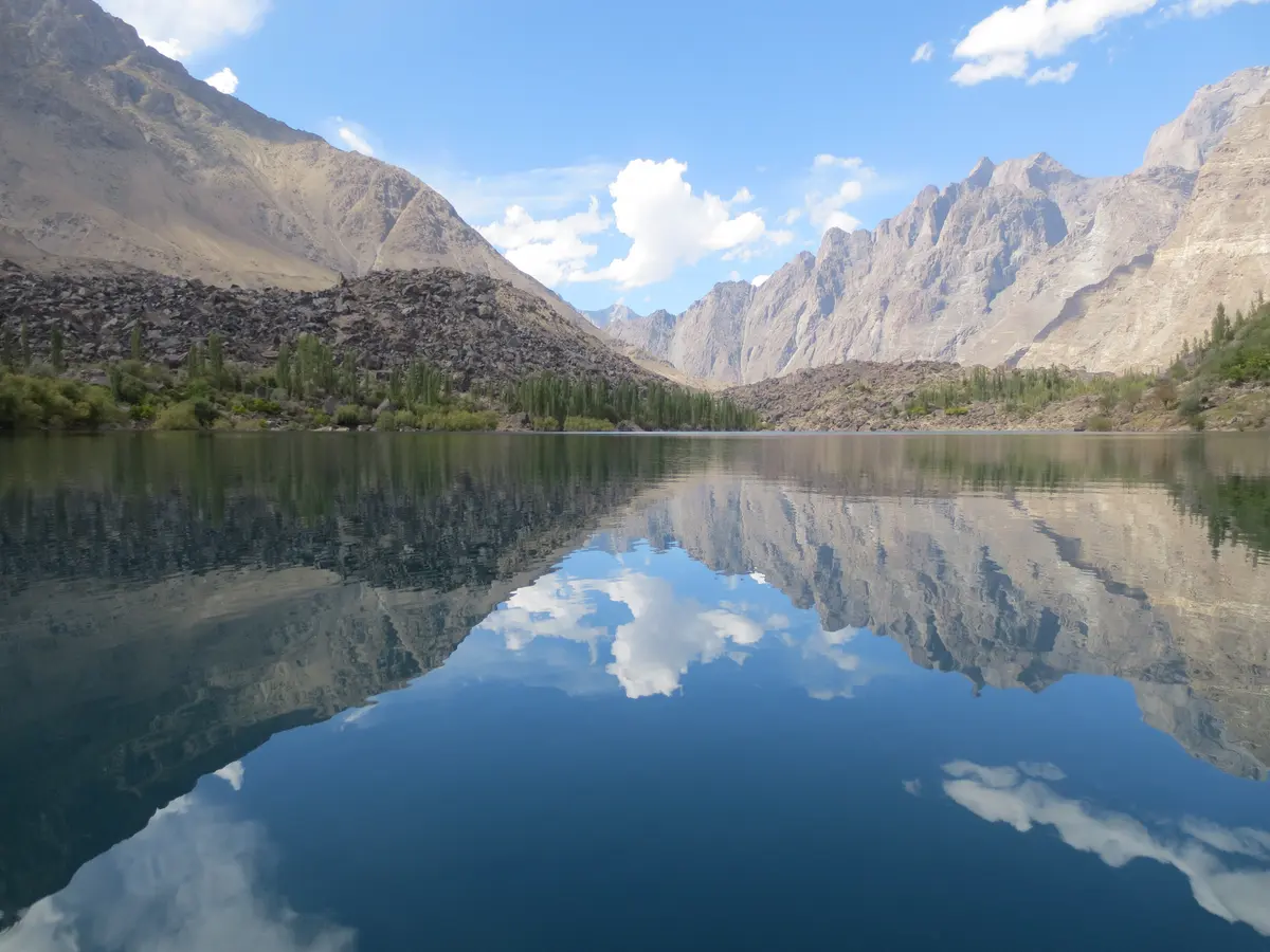 Mirror-still water of Upper Kachura Lake reflecting bare mountains and cloud, Skardu
